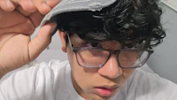 a man wearing glasses and a hat with curly hair