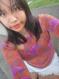 a woman in a colorful top and shorts is posing for a photo