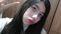a girl with long hair making a peace sign